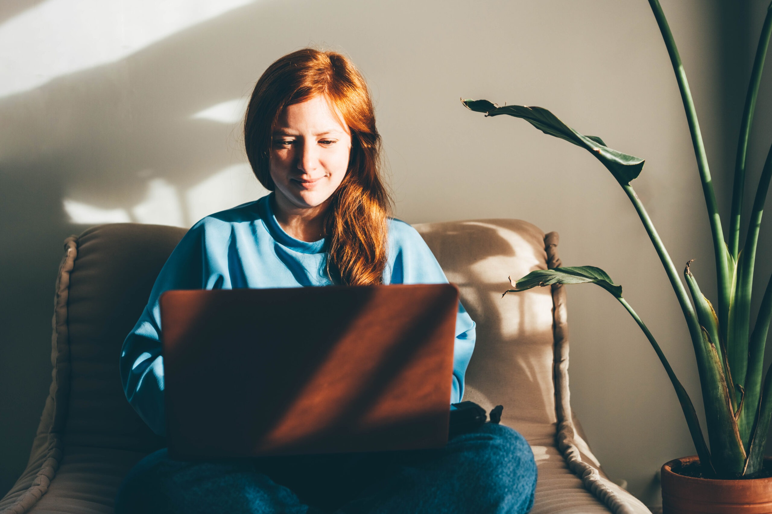 Young woman with laptop working in living room.